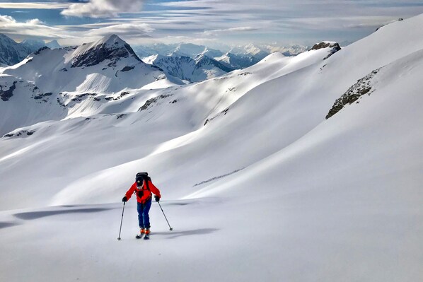 A skier on a snow-covered mountain slope with distant peaks.