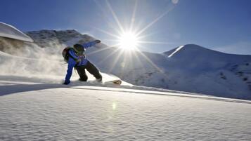A snowboarder on a snowy slope with a clear sky and sun shining.