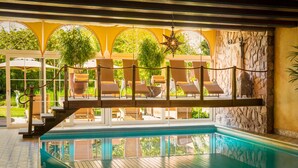 Un espace piscine avec des chaises longues et un escalier menant à un espace de détente abrité.