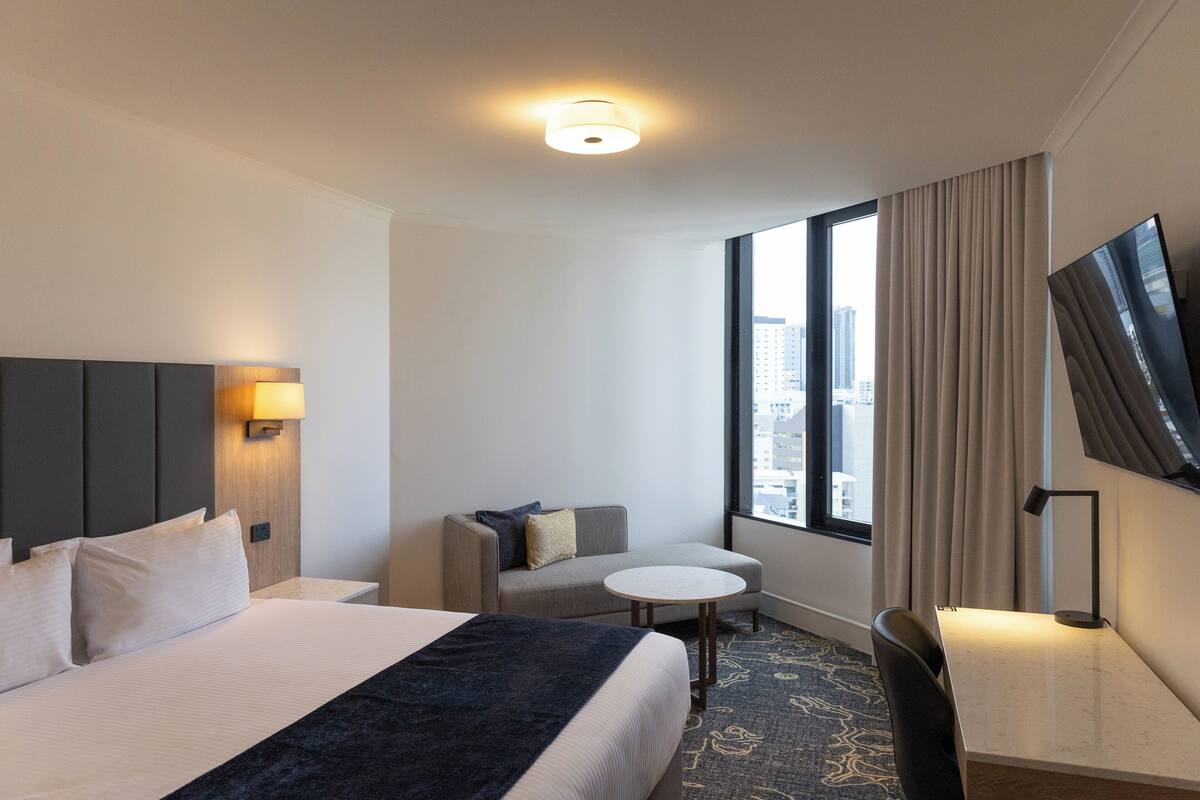 Een hotelkamer met een groot bed, een bank, een tafeltje, een bureau en een televisie.