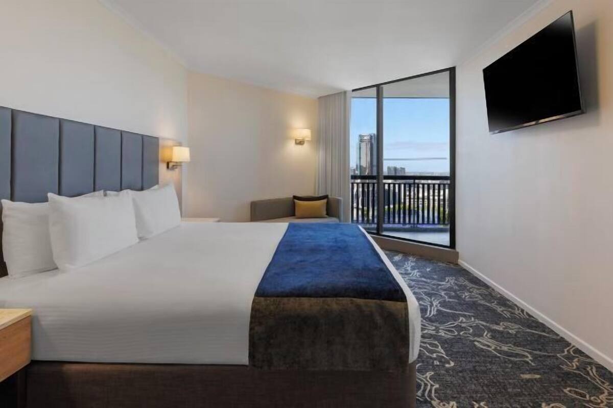 Een hotelkamer met een groot bed, een aan de muur bevestigde televisie en een balkon met uitzicht.