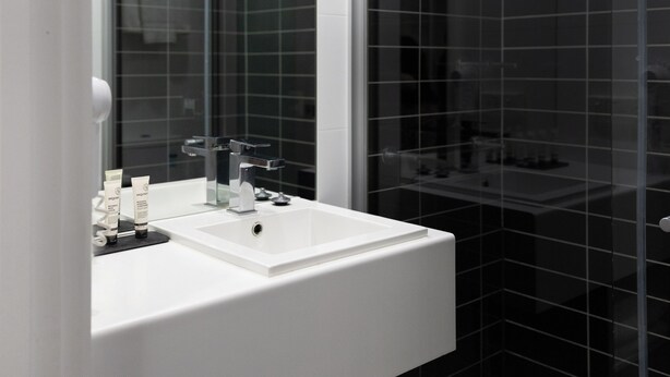 Een moderne badkamer met een wit wastafelmeubel, een spiegel en een douchecabine met glazen wanden.