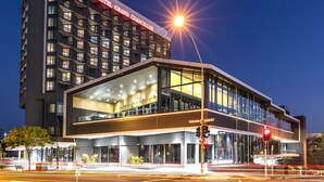Een modern hotel met een opvallend 'Hotel Grand Chancellor' bord, grote glasramen en een goed verlichte gevel.