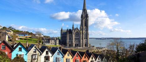 A coastal town with colorful terraced houses and a prominent Gothic-style church with a tall spire.