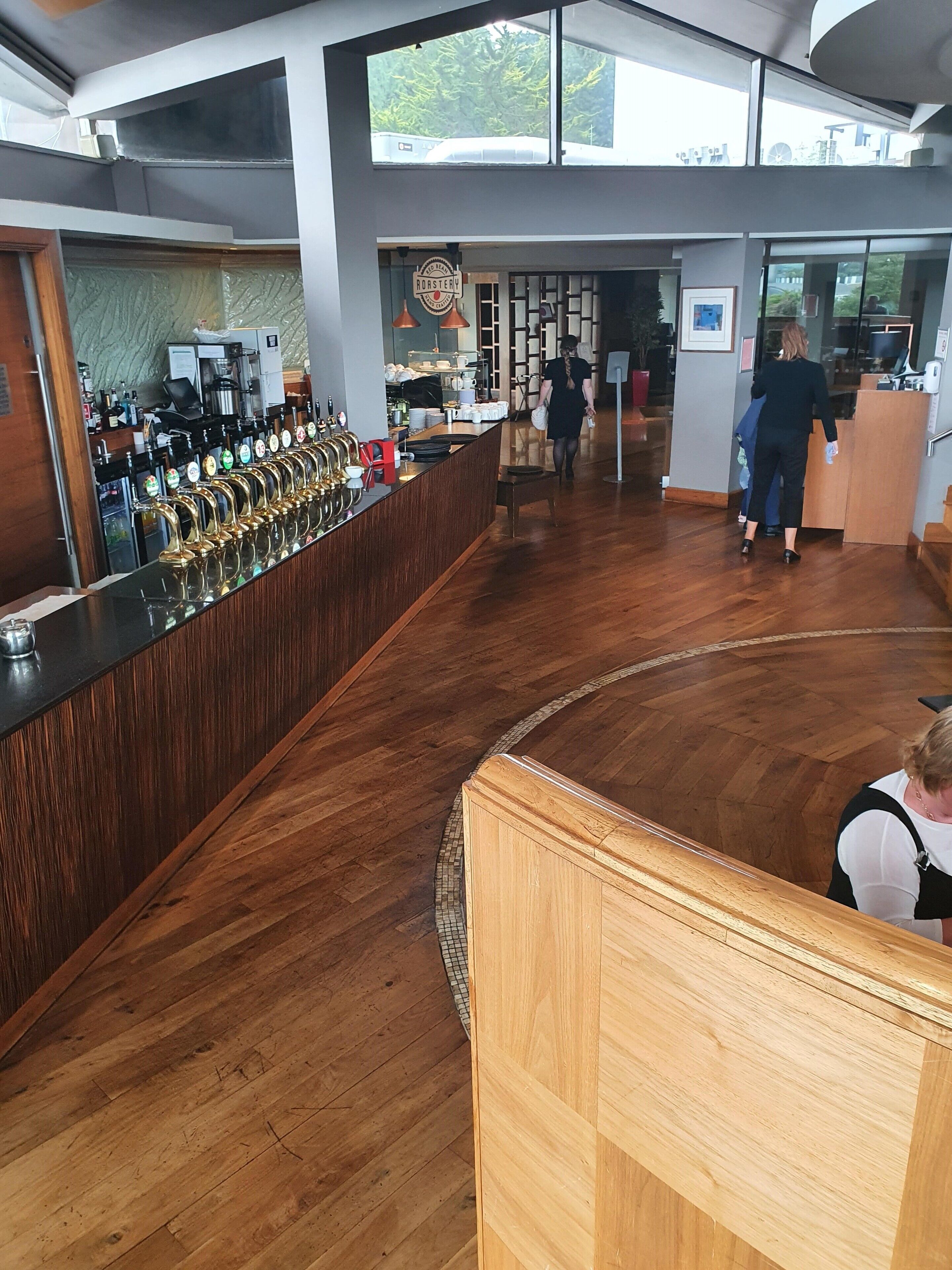 Una zona de bar con una barra larga, múltiples grifos y suelo de madera.