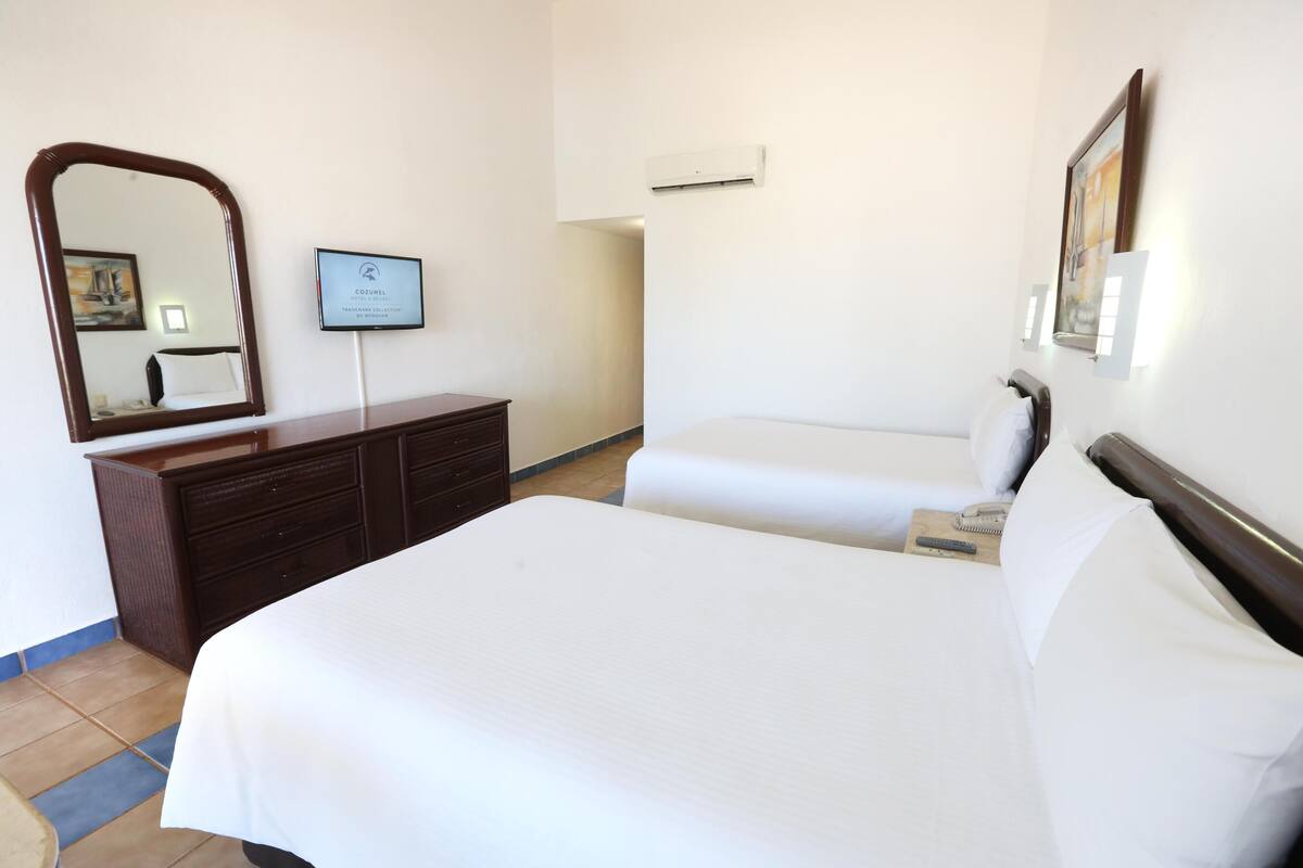 Una habitación de hotel con una cama grande, un aparador, un espejo y un certificado enmarcado en la pared.