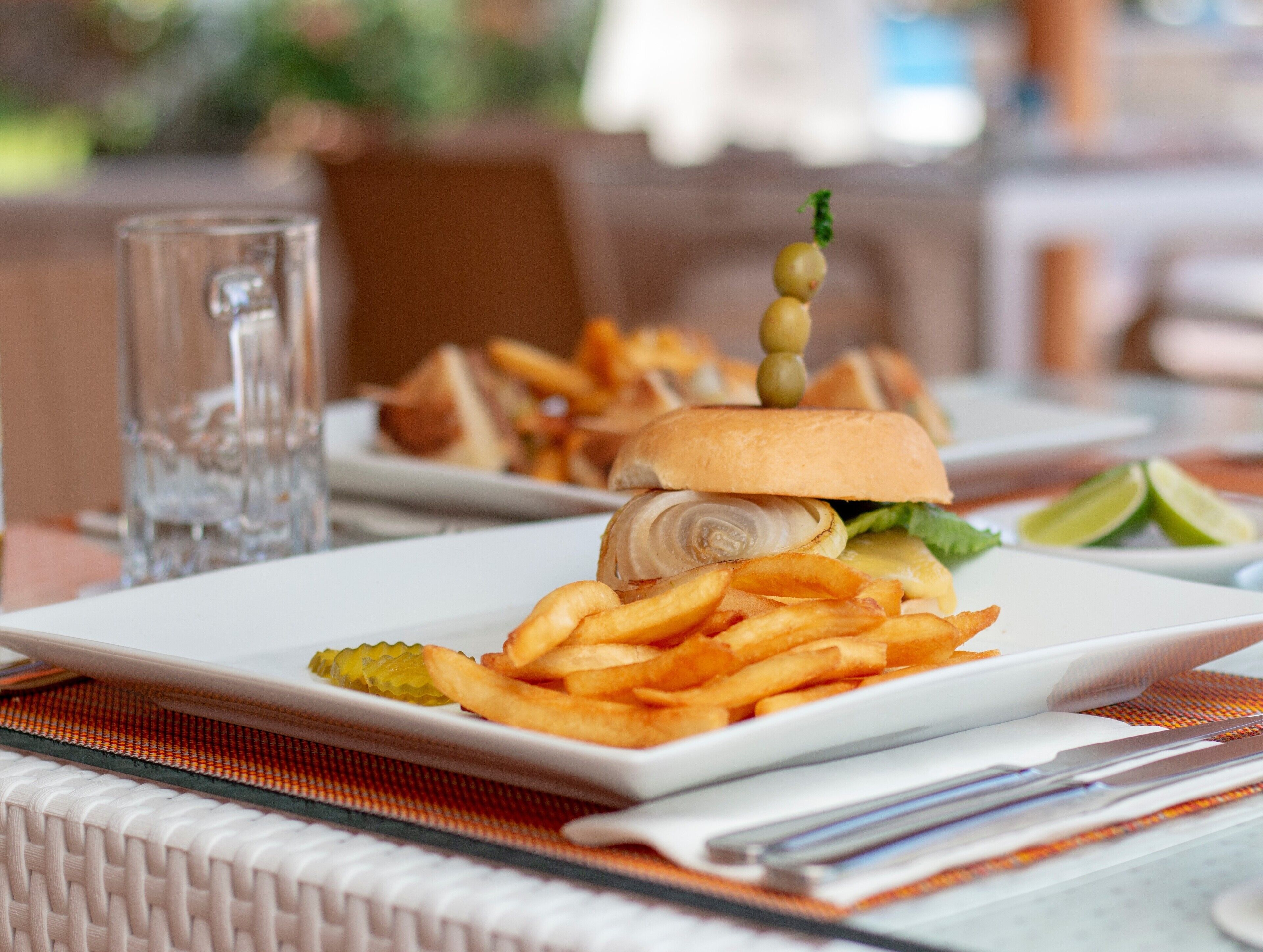 A plate of food with a sandwich, fries, and a glass of water.