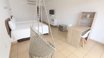 Une chambre à coucher avec un lit, un fauteuil suspendu, un bureau et un téléviseur.