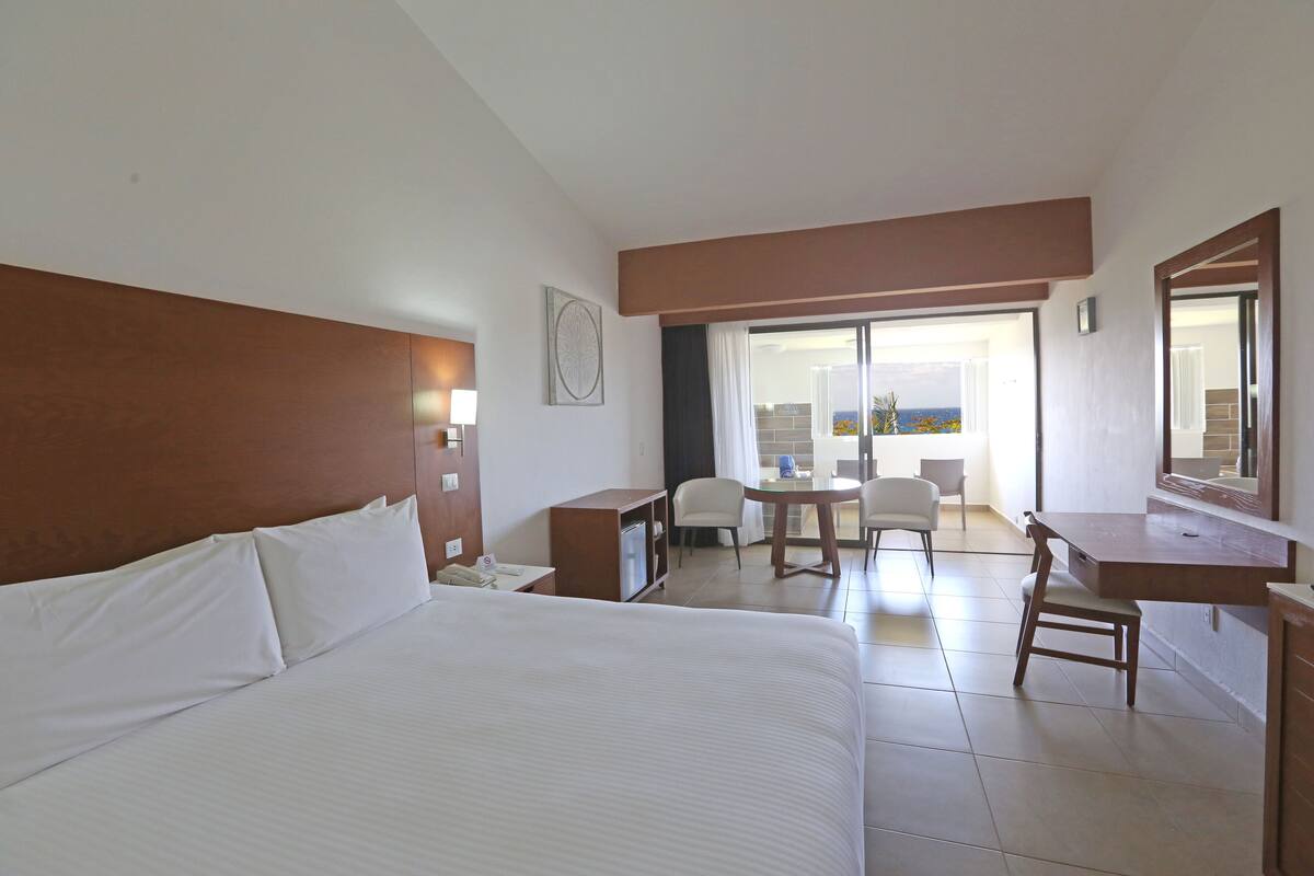 Une chambre d’hôtel avec un grand lit, un bureau, une chaise et un balcon avec vue.