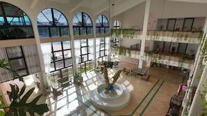 A spacious atrium with high ceilings, large arched windows, and a central fountain. - Cozumel Hotel & Resort (Cozumel)