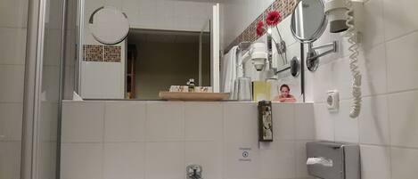 Un baño con lavabo, espejo y perchero para toallas.