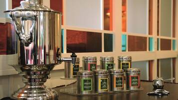 A stainless steel samovar and several metal containers with labels on a counter.