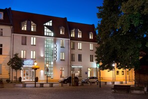 Ein Hotel mit markantem Eingang, einem Parkplatz und einer gut beleuchteten Straße.