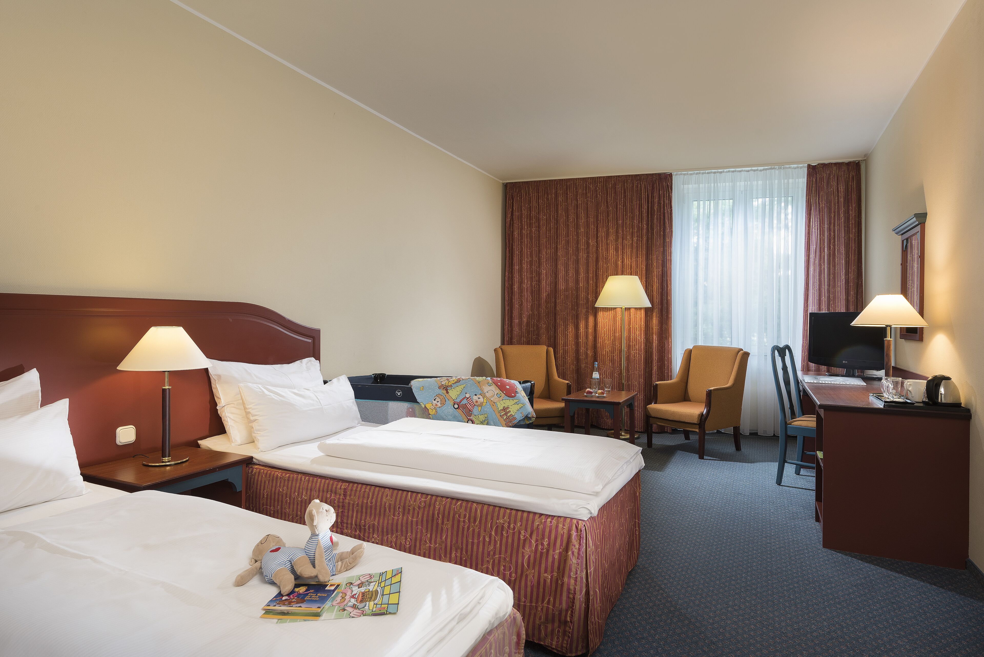Een hotelkamer met twee bedden, een bureau, een stoel, een televisie en een lamp.