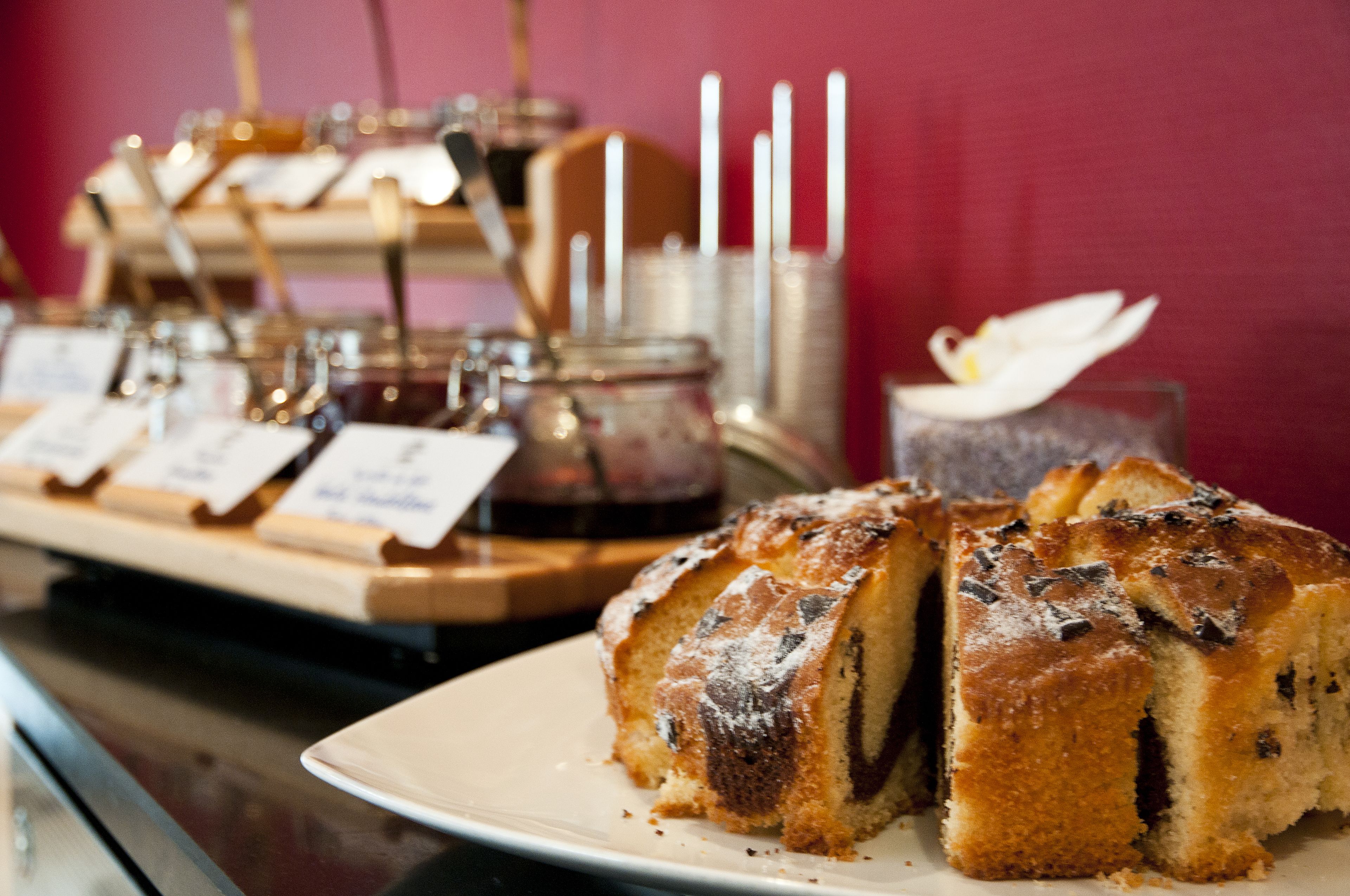 A dessert display with a bundt cake and a cake with a white flower on top.