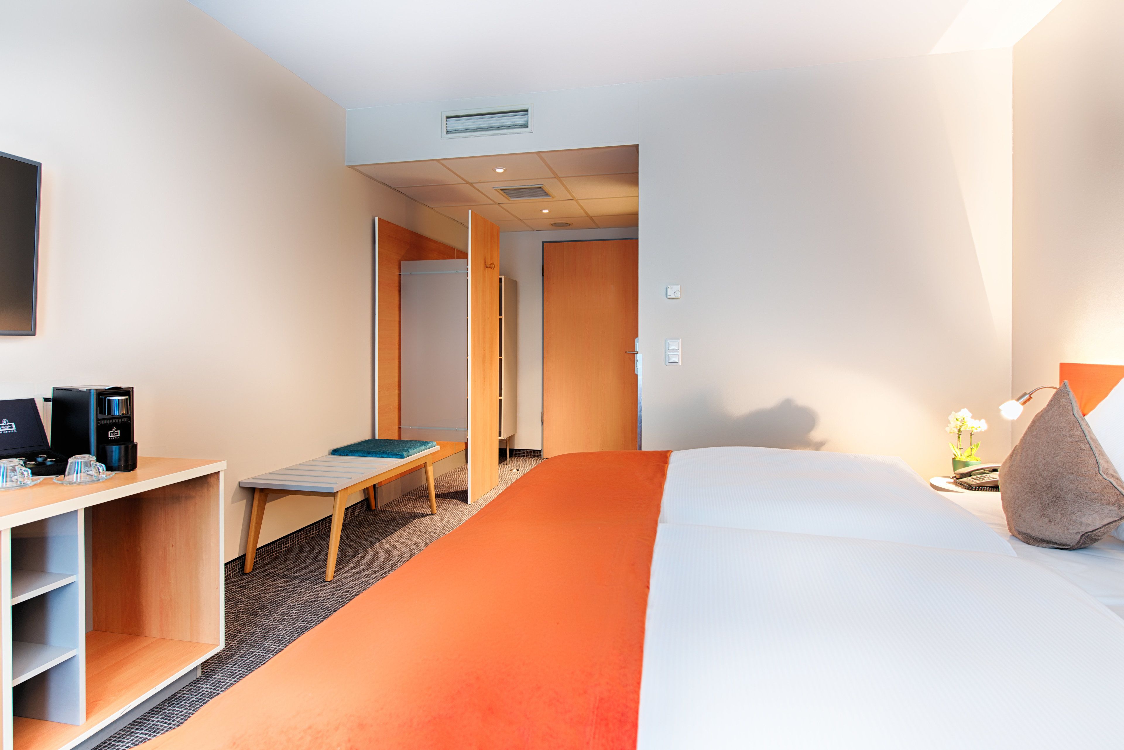 Una camera d'albergo con un letto, una scrivania, una sedia, un tavolino e un armadio.