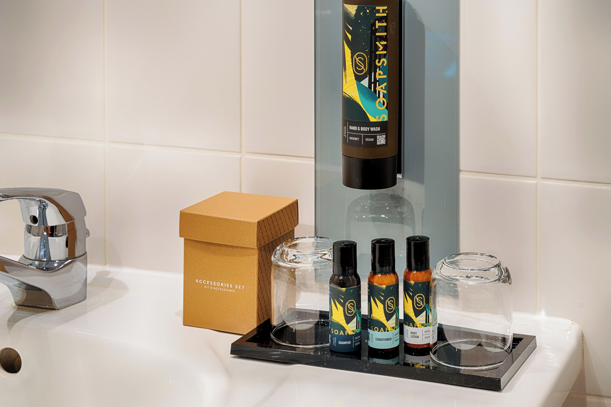 A bathroom sink with a chrome faucet, a soap dispenser, and a box labeled "ACCESSORIES SET".