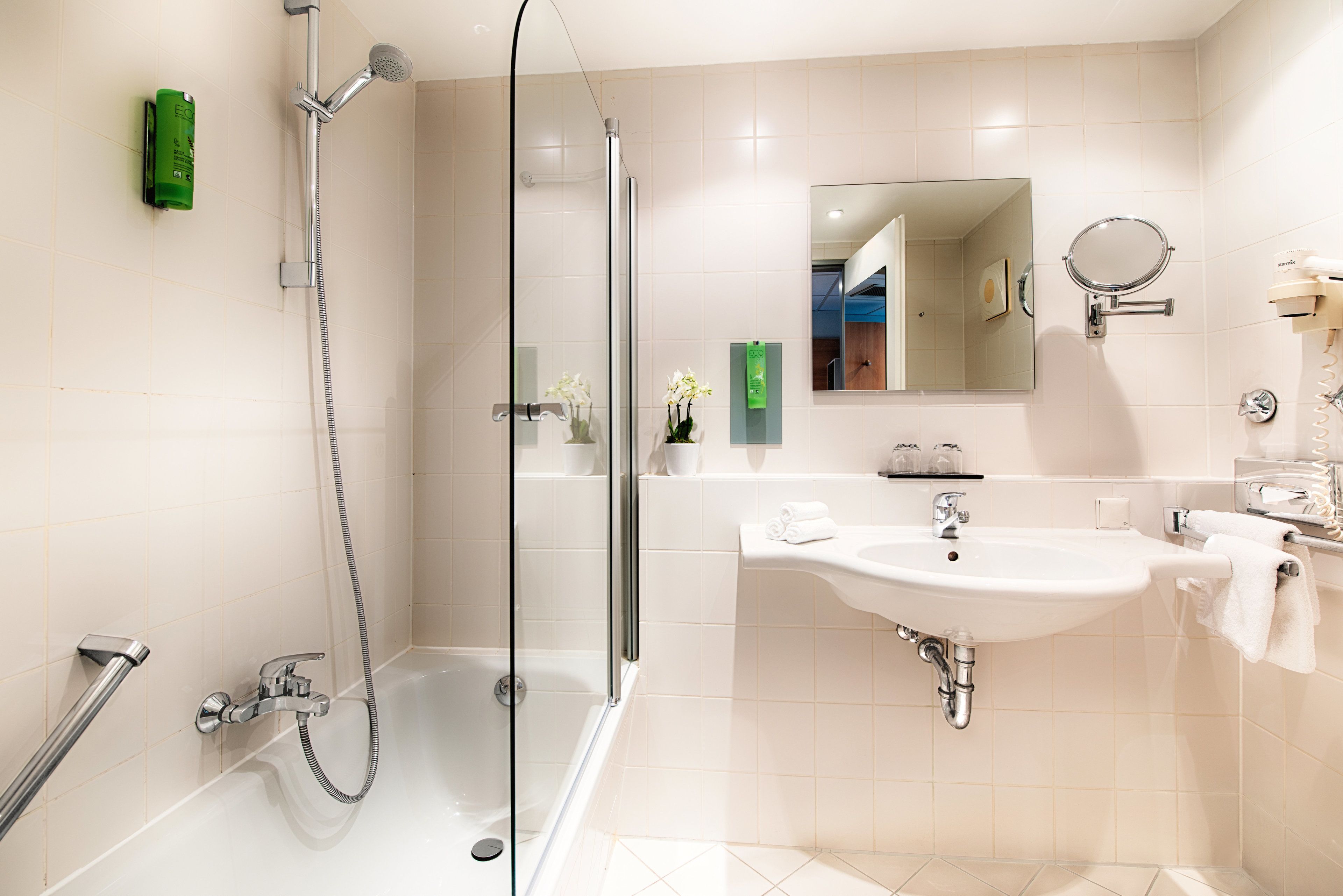 Een moderne badkamer met een douchecabine van glas, een wastafel en een spiegel.