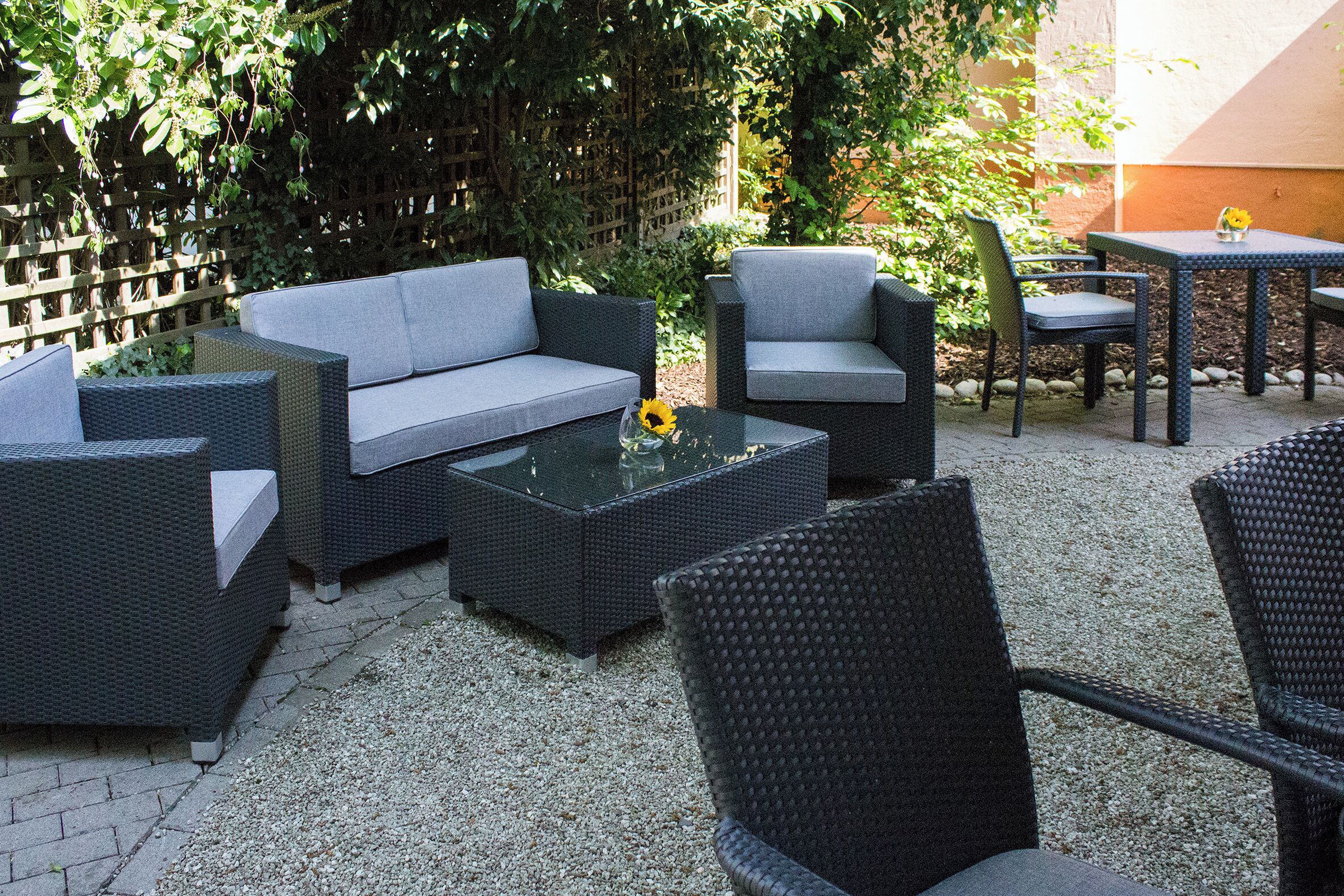 An outdoor patio with wicker furniture, including a sofa, chairs, and a table.
