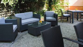 Eine Außenpatio mit Korbmöbeln, darunter eine Couch, Stühle und ein Tisch.