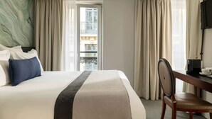 A hotel room with a bed, a desk, a chair, and a television. - Hotel Queen Mary Paris (Paris)