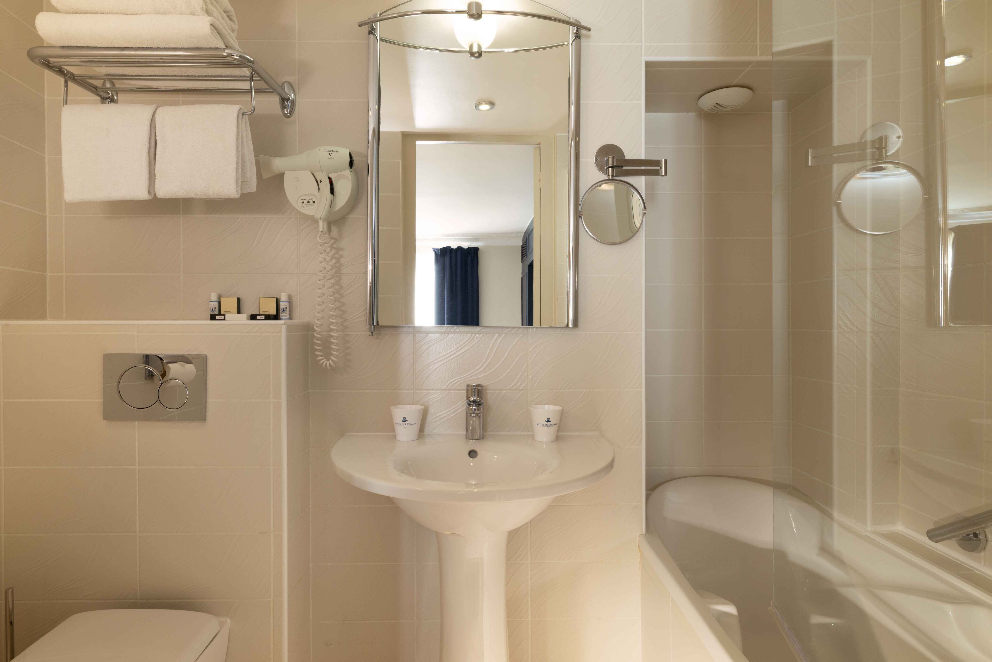 Une salle de bain équipée d’un lavabo, d’un miroir, d’un porte-serviettes et d’une douche.