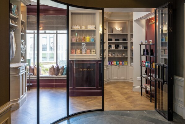 A hotel lobby with a seating area, a reception desk, and a variety of amenities including a minibar and a display of toiletries. - Old Course Hotel (St. Andrews)