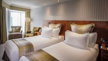 Hotellihuone, jossa on kaksi sänkyä, puinen pääty ja yöpöytälamppu sekä tuoli.