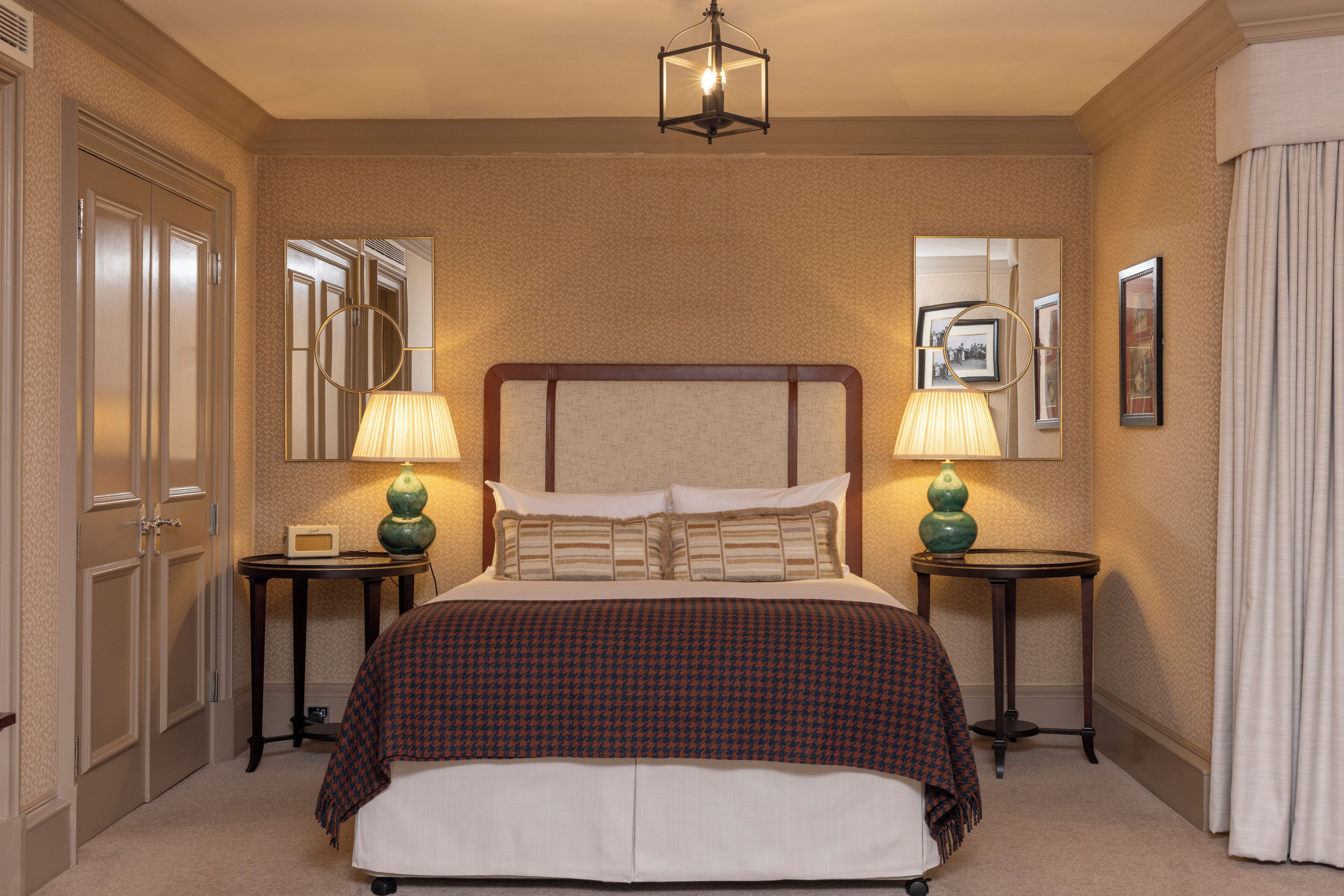 A hotel room with a large bed, two bedside tables with lamps, a mirror, and a view of the sea.