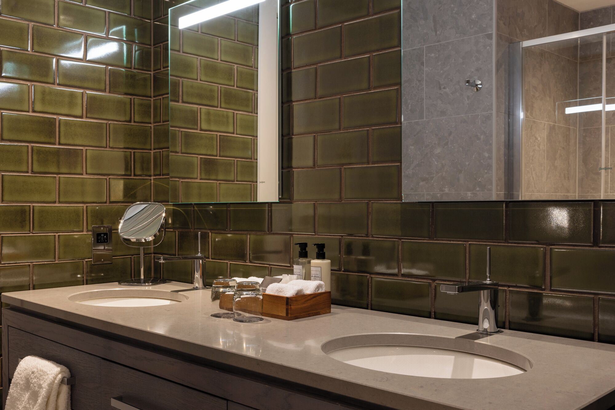 A modern bathroom with two sinks, a mirror, and a towel rack.