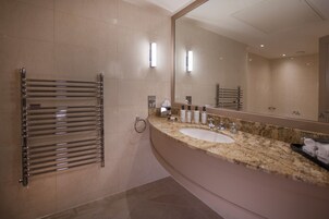 Un baño moderno con un espejo grande, un toallero cromado, una encimera de granito y un lavamanos.