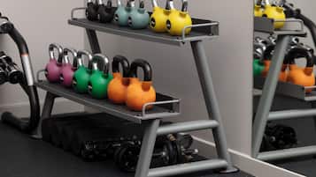 A gym with kettlebells on a rack and a mirror reflecting the kettlebells.