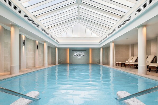 A large indoor swimming pool with a high ceiling and skylights, surrounded by columns and lounge chairs. - Old Course Hotel (St. Andrews)