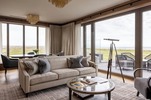 A modern living room with a sofa, coffee table, and a telescope. - Old Course Hotel (St. Andrews)