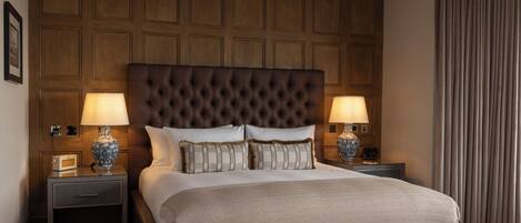 Habitación de hotel con una cama grande, dos mesitas de noche, un cabecero de madera y una cortina.