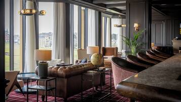 A hotel lobby with a leather sofa, a globe, and a view of the city through large windows.
