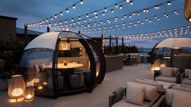 A rooftop terrace with string lights, outdoor seating, and a glass-enclosed dining area. - Old Course Hotel (St. Andrews)