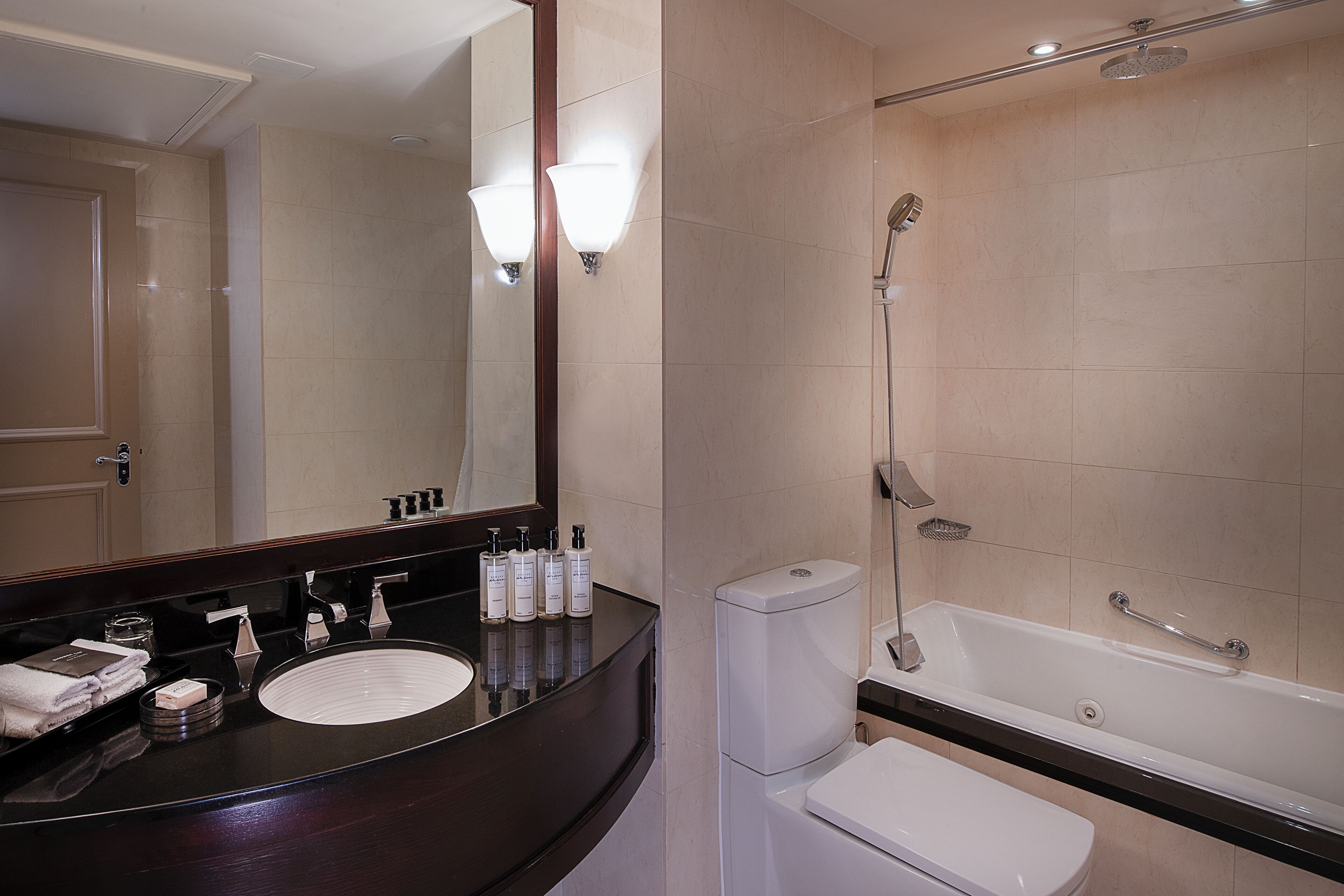 A modern bathroom with a dark wooden vanity, a white sink, a toilet, and a bathtub.