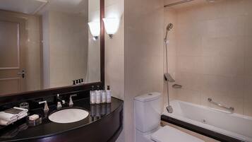 A modern bathroom with a dark wooden vanity, a white sink, a toilet, and a bathtub.