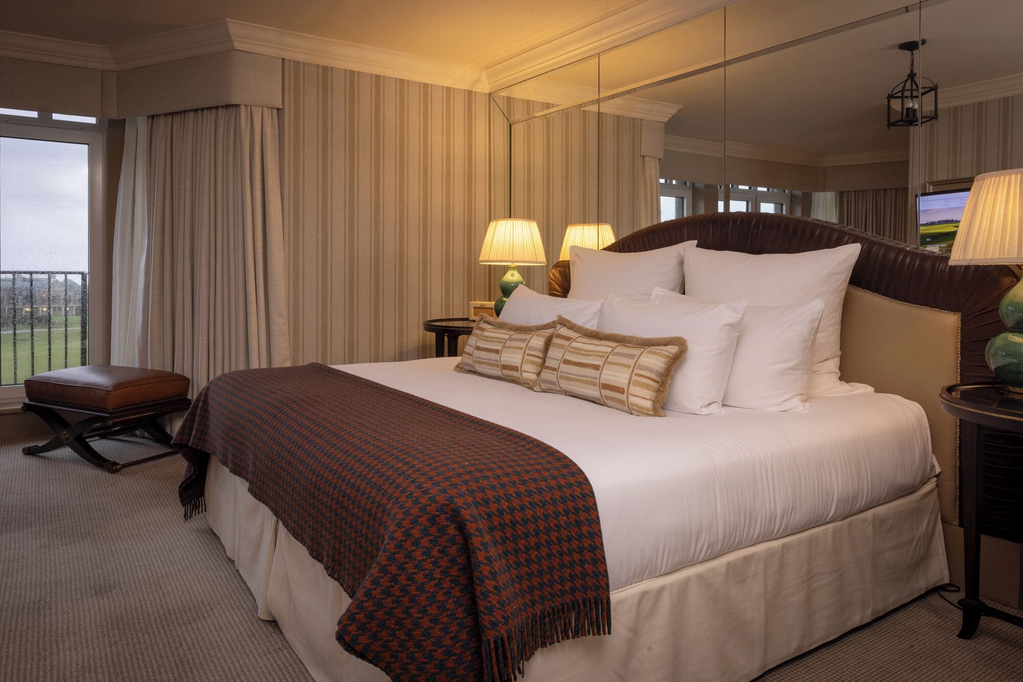 Habitación de hotel con una cama grande, zona de estar y vistas por la ventana.
