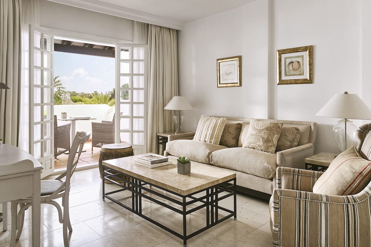 A living room with a sofa, armchairs, a coffee table, and a dining area with a table and chairs.