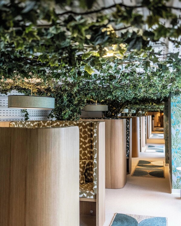 A corridor with wooden partitions, a patterned carpet, and a hanging plant installation.