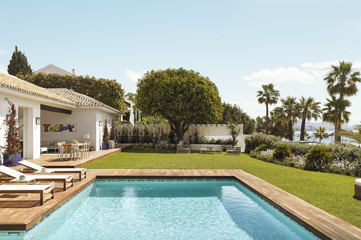 A poolside area with lounge chairs, a small patio, and a view of the sea.