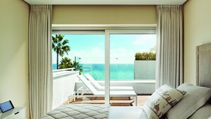 A hotel room with a bed, a TV, and a balcony with a view of the ocean. - Puente Romano Marbella (Marbella)