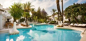 Relax by the serene pool surrounded by lush greenery and Mediterranean-style architecture.