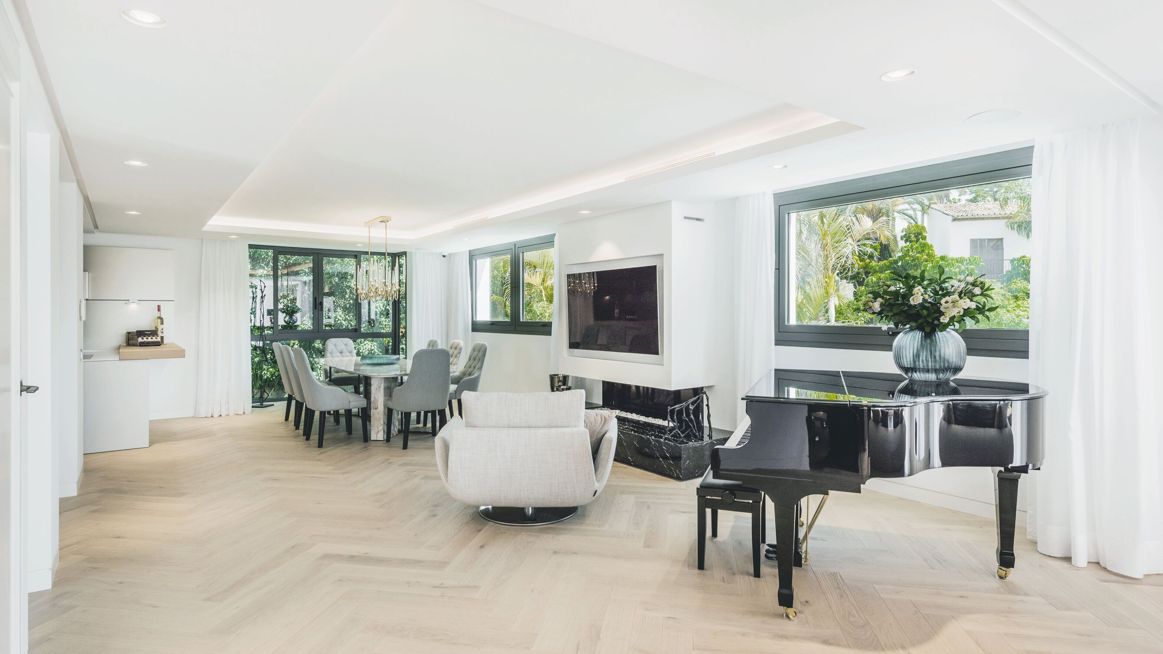 A spacious living area with a dining table, chairs, a piano, and a TV.