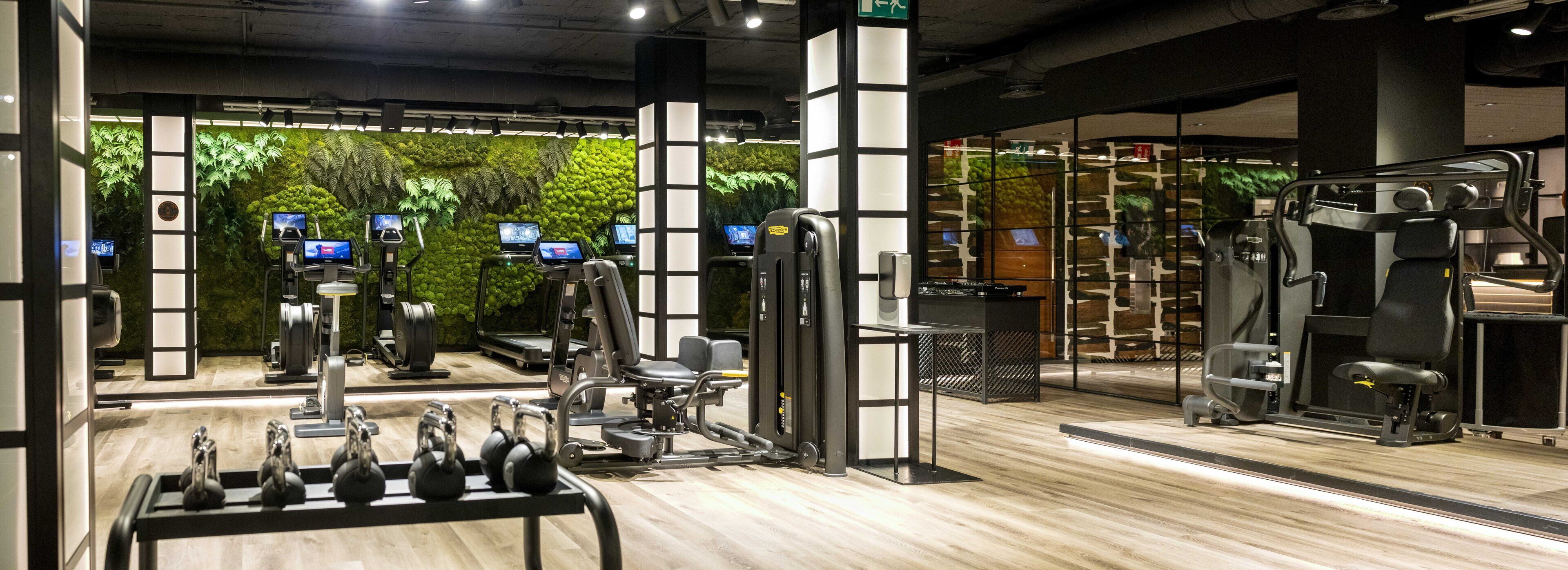 A modern gym with various exercise equipment, including treadmills, weight machines, and free weights.