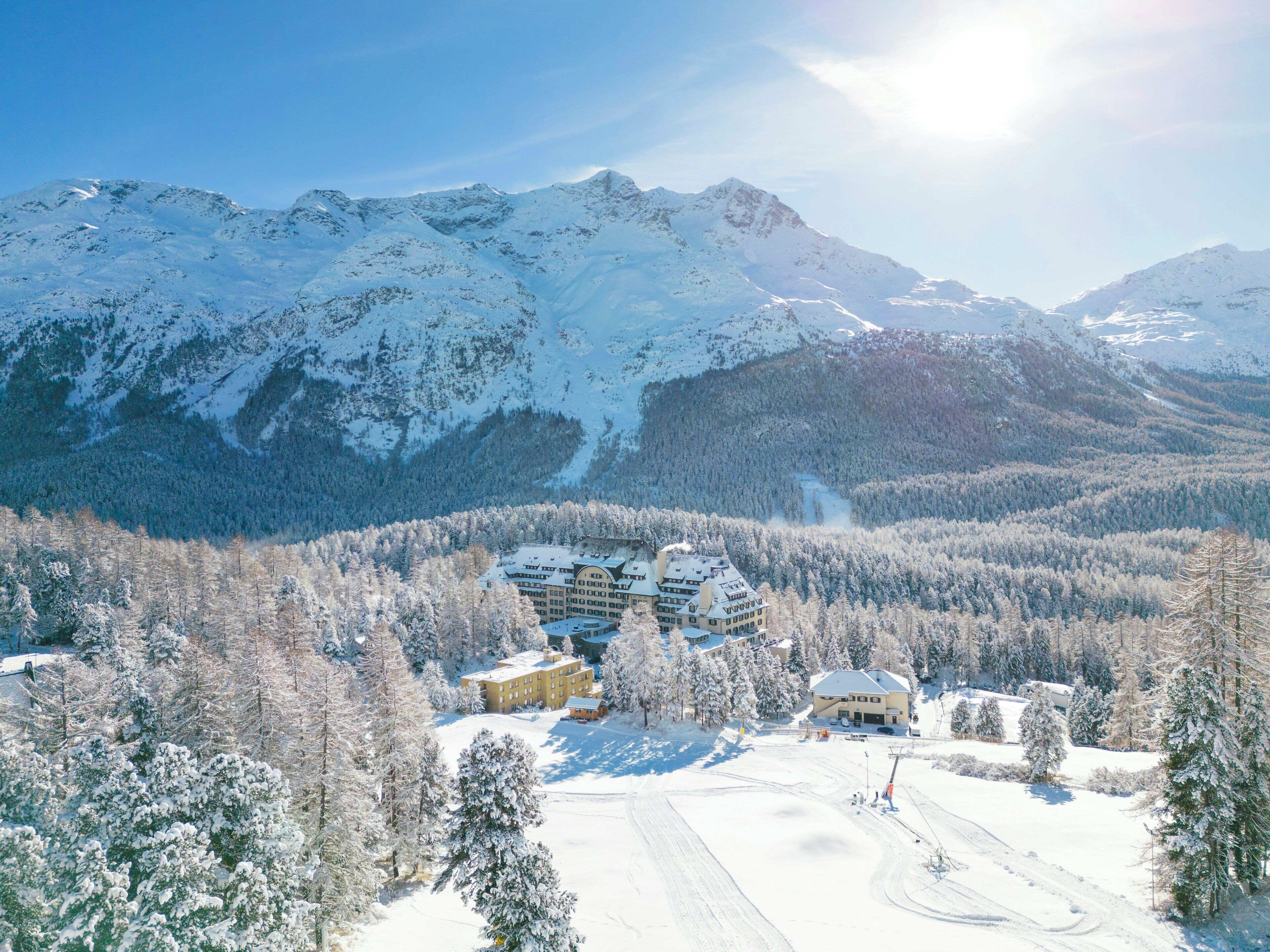 Ein schneebedecktes Bergresort mit mehreren Gebäuden, Skipisten und bewaldeten Gebieten.