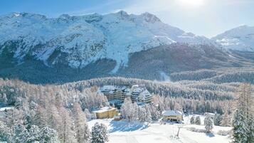Ein schneebedecktes Bergresort mit mehreren Gebäuden, Skipisten und bewaldeten Gebieten.