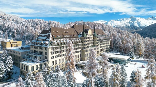 Ein großes Hotel mit mehreren Gebäuden, umgeben von schneebedeckten Bäumen und Bergen.